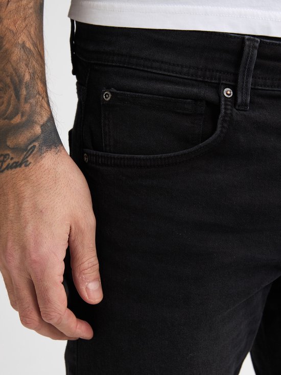 Detailopname van een zwarte jeans met een coin pocket.
