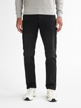 Man van voren gezien, draagt een grijze sweater en zwarte jeans met witte sneakers.