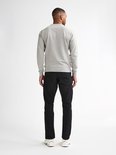 Man van achteren gezien, draagt een grijze sweater en zwarte jeans.