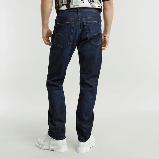 Donkerblauwe G-Star jeans, gedragen door een man. Zicht op de achterkant en zijkanten.