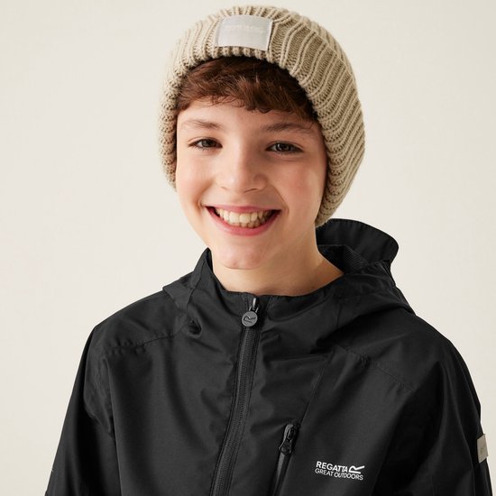 Glimlachende jongen met beige muts en zwarte jas met capuchon, logo op borst.