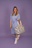 Blauwe jurk met strik in de taille, gedragen door een blonde vrouw met een gestreepte tas.