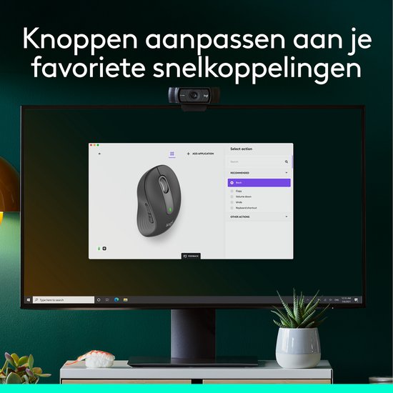 Grijze Logitech M650 L muis op een computerscherm dat de "Select action" instellingen toont. Een webcam staat bovenop het scherm.