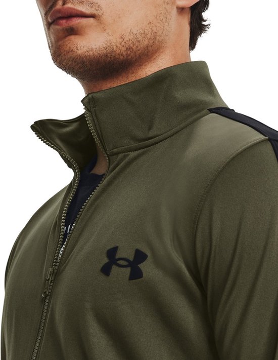 Detailopname van de kraag van een groen Under Armour trainingsjack met een zwart logo.