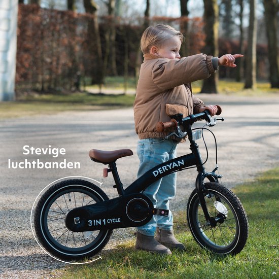 Bambin pointe du doigt un vélo Deryan noir avec guidon et selle marrons. Le vélo a des 'pneus gonflables robustes'.