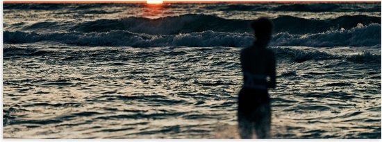 Poster Glanzend – Silhouet van Vrouw in de Wilde Zee tijdens Zonsopkomst - 60x20 cm Foto op Posterpapier met Glanzende Afwerking