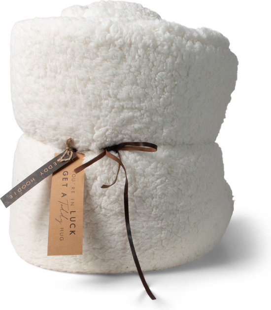 Een opgerolde witte teddy deken, vastgebonden met bruin lint en voorzien van twee labels: "GET A LUCKY BEAR HUG" en "YOU'RE IN".