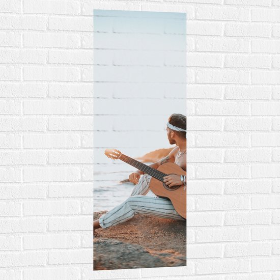 Muursticker - Hippie Man met Gitaar op Rots aan de Zee - 40x120 cm Foto op Muursticker