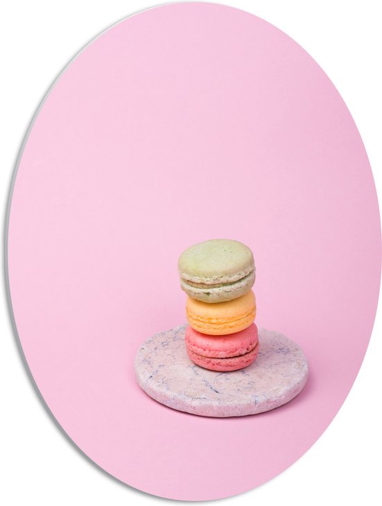 PVC Schuimplaat Ovaal - Drie Opgestapelde Macarons in Verschillende Kleuren tegen Roze Achtergrond - 42x56 cm Foto op Ovaal (Met Ophangsysteem)