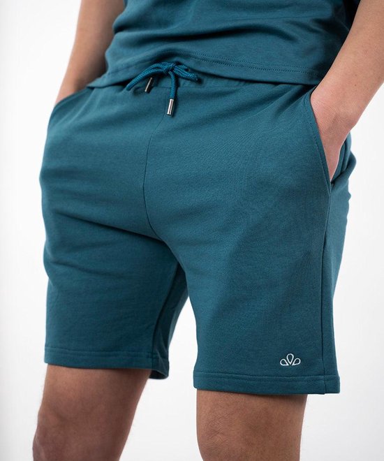 Close-up van een blauwe short met witte geborduurde bloemlogo en koord.