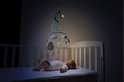 Baby in een wiegje kijkt omhoog naar een blauwe muziekmobiel met een lachende maan.