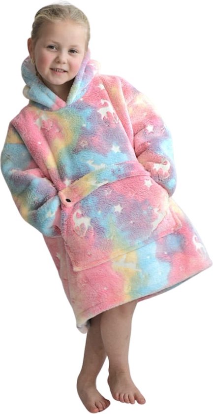 Een meisje met blonde staartjes staat, gekleed in een pluche hoodie deken met pastel regenboogkleuren, sterren en eenhoorns. Witte achtergrond.