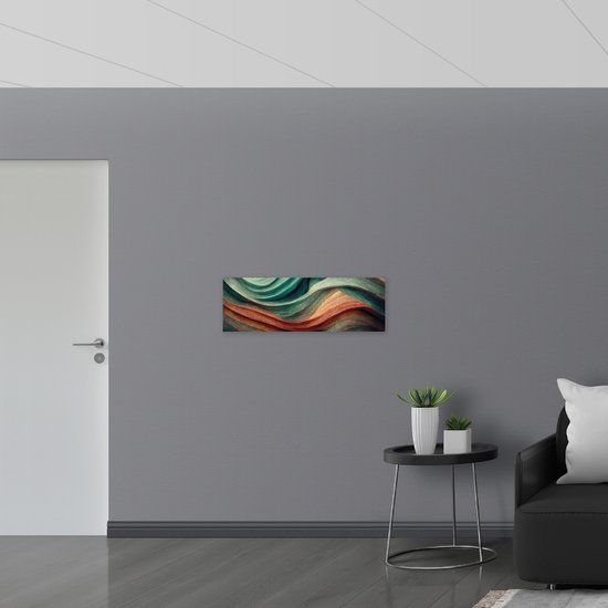 Abstract schilderij met golvende vormen in groen en oranje tinten, hangend aan een grijze muur.