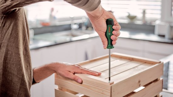 Man monteert een houten krat met een Bosch schroevendraaier met groen handvat.