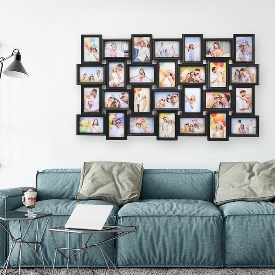 Un grand cadre photo noir avec 28 photos de familles et de couples accroché à un mur blanc.