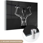 MuchoWow® Glasschilderij 150x100 cm - Schilderij acrylglas - Een vrouw houdt twee gewichten omhoog tijdens fitness - zwart wit - Foto op glas - Schilderijen