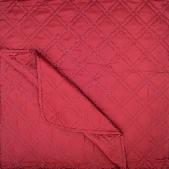Gevouwen rode sprei met ruitpatroon en een omgeslagen hoek.