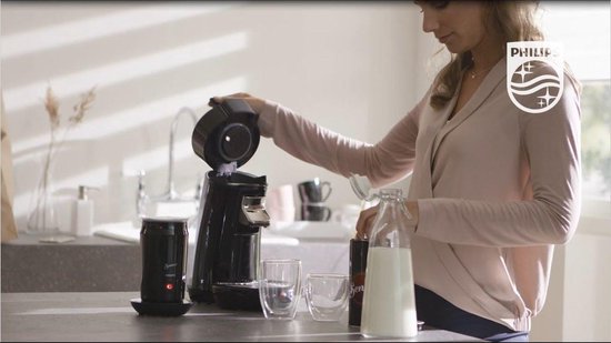 Vrouw met een zwarte Philips Senseo melkopschuimer met een rode aan/uit-knop.