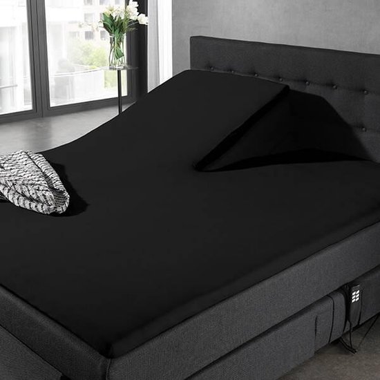 Een verstelbaar zwart bed met een gedraaid hoeslaken en een deken.
