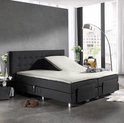 Verstelbaar bed met creme splittopper hoeslaken, donkergrijs gestoffeerd hoofdbord en ombouw.