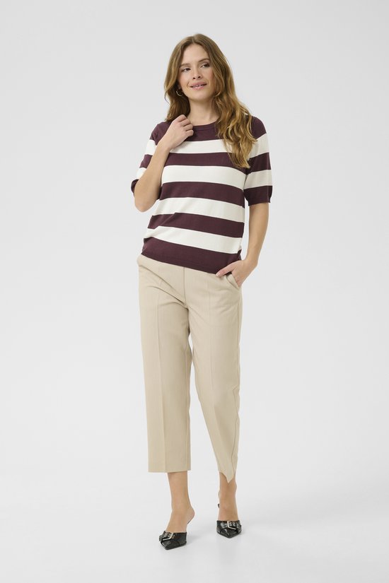Model met bordeauxrode en witte gestreepte trui met korte mouwen en beige broek.