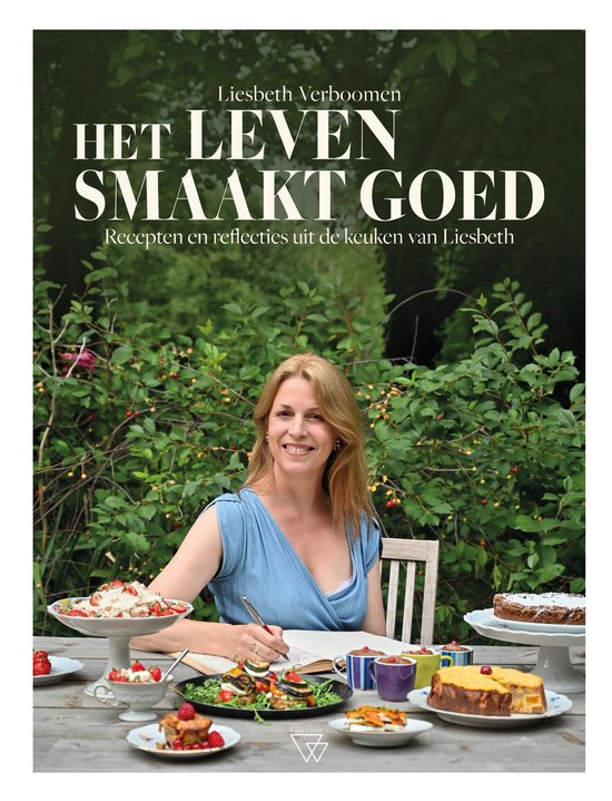 Liesbeth Verboomen met de titel 'Het leven smaakt goed', recepten en reflecties uit de keuken van Liesbeth. Ze zit aan tafel met een grote diversiteit aan gerechten.