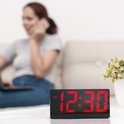 Digitale wekker met rood display dat 12:30 weergeeft, op een tafel.