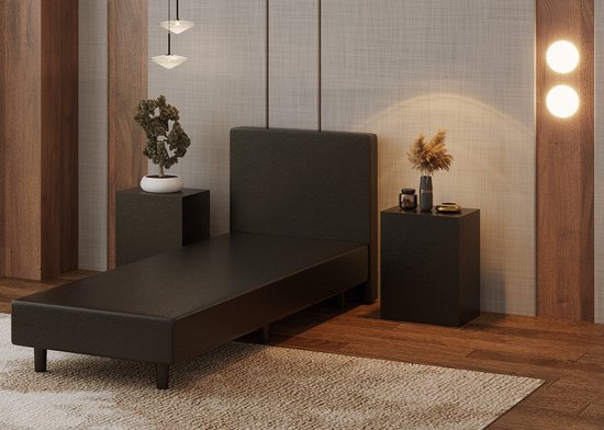 Zwarte boxspring zonder matras, met een hoofd- en voeteneind.