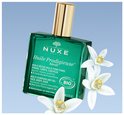 Groene Nuxe Huile Prodigieuse Néroli fles met gouden dop en witte bloesems.