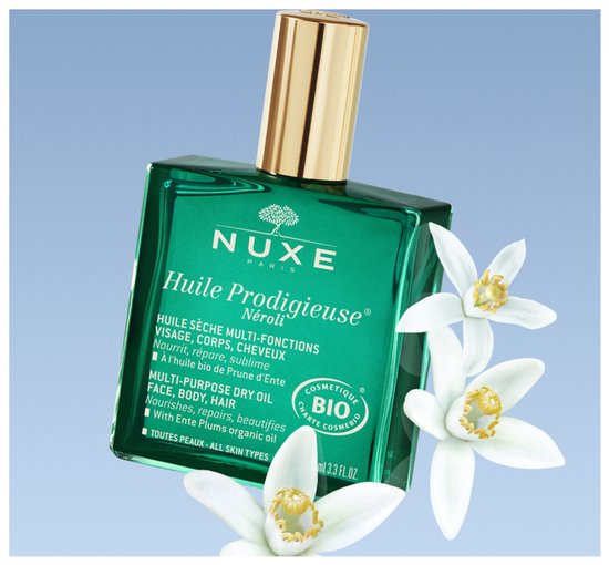 Groene Nuxe Huile Prodigieuse Néroli fles met gouden dop en witte bloesems.