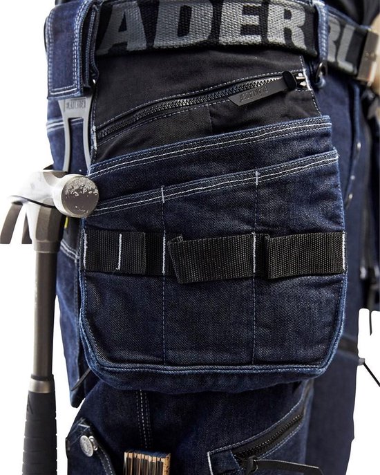 Detail van een blauwe werkbroek met hamer, gereedschapszakken en Blaklader riem.