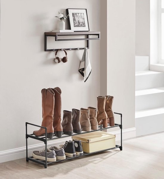 Zwart 2-laags schoenenrek met laarzen, schoenen en een doos. Wandrek erboven.