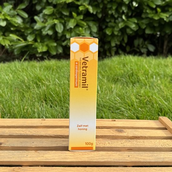 Vetramil zalf met honing, 100g tube, oranje en witte verpakking met honingraatmotief.