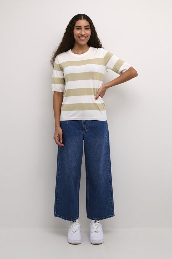 Vrouw in gestreepte trui met off-white en beige strepen en wijde jeans.