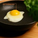 Gebakan ei in een zwarte koekenpan met granieten look, met tekst 'ANTI-AANBAKLAAG'.