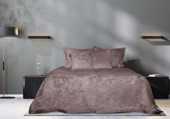 Gedrapeerd bed met een paars sprei en twee kussens in een slaapkamer.