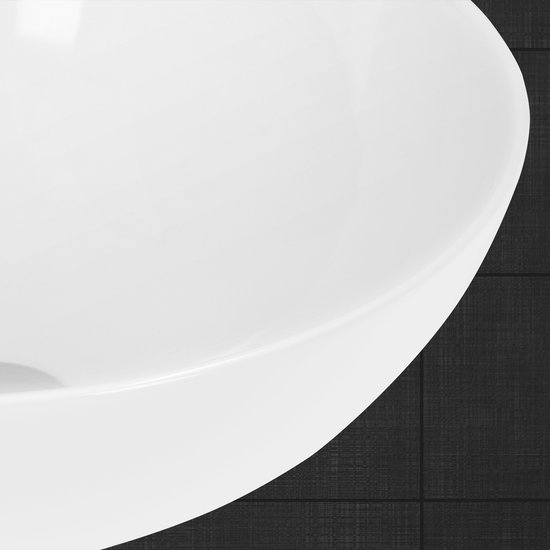 Détail du bord incurvé d'un lavabo rond en céramique blanche.