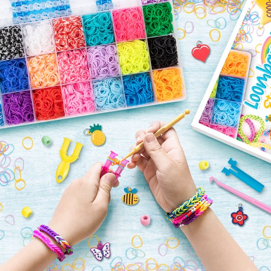 Kinderhanden maken armbandjes met loom, loombandjes in vele kleuren, met kralen, charms en gereedschap.