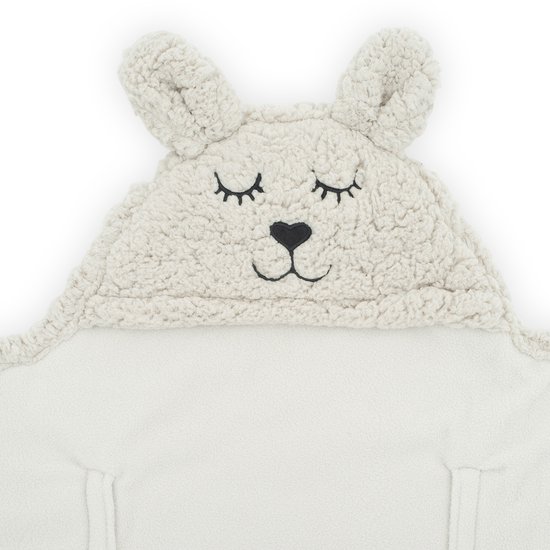 Sluit aan op een beige baby wikkeldeken met konijnenoren en een geborduurd gezichtje.