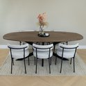 Table à manger avec huit chaises en tissu de couleur claire et un vase avec des fleurs séchées.