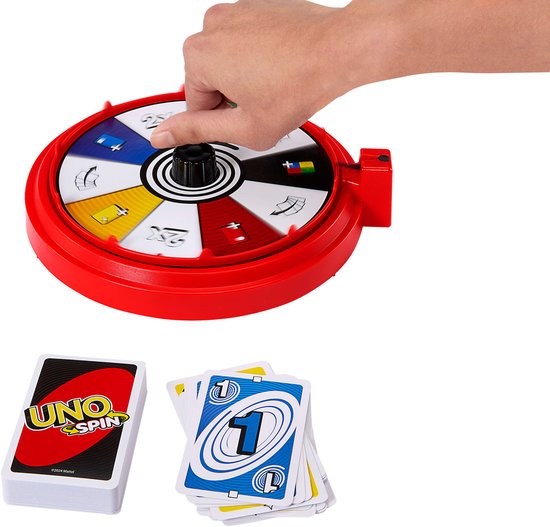 Hand draait aan het rode UNO Spin wiel, met een stapel kaarten en losse kaarten ernaast.