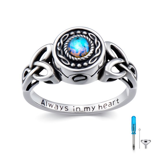 Zilveren urnring met Keltische knopen en een heldere blauwe steen in het midden. Binnenin de ring staat de tekst 'Always in my heart'.