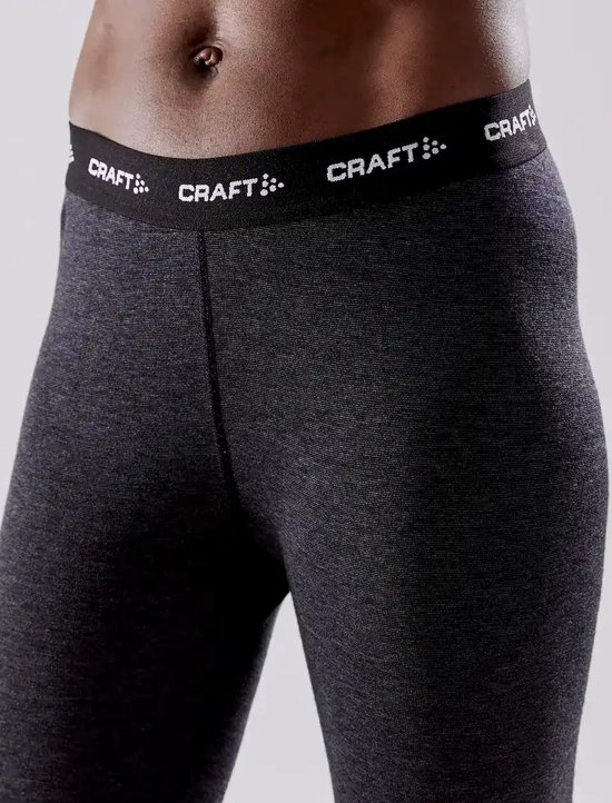 Close-up van de donkergrijze thermobroek van een vrouw, met gestructureerde stof en 'CRAFT' logo tailleband.