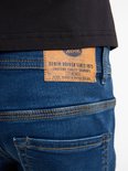 Detail van het leren label op de achterkant van een blauwe jeans met stiksels.