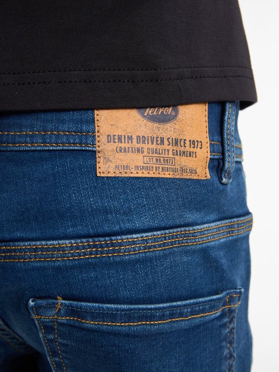Detail van het leren label op de achterkant van een blauwe jeans met stiksels.