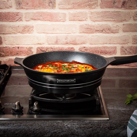 Zwarte Royalty Line koekenpan met marmeren anti-aanbaklaag staat op een gasfornuis en wordt gebruikt om een gerecht met eieren en saus te koken.