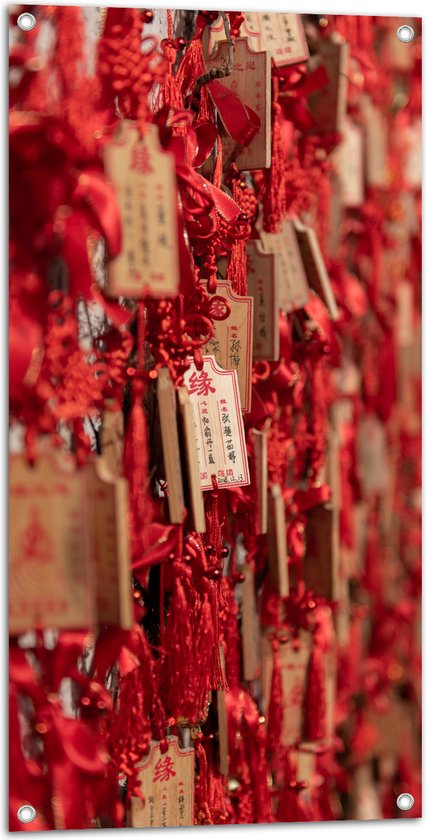 Tuinposter – Rode Sleutelhangers met Chinese Tekens aan een Muur - 50x100 cm Foto op Tuinposter (wanddecoratie voor buiten en binnen)