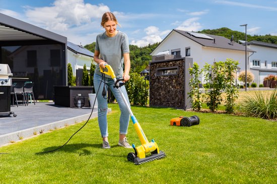 Vrouw gebruikt gele Gloria Multibrush op gras in de tuin.