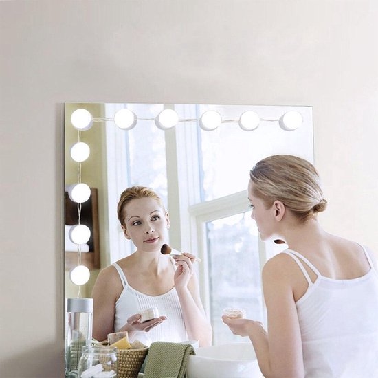 Vrouw met make-up kwast, spiegellampjes in de spiegel.