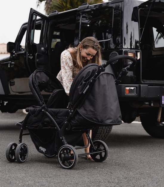 Zwarte dubbele buggy naast een zwarte jeep, een vrouw buigt over de buggy.